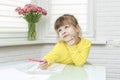 Little girl sits at a table in a white room and draws Royalty Free Stock Photo