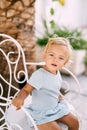 Little girl sits on a white forged chair