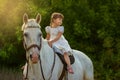 The little girl sits on a horse astride