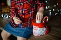 A beautiful little blonde in a traditional plaid shirt opens a chocolate bar from her sweet Christmas gift Royalty Free Stock Photo