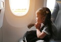 Little girl sitting in airplane and praying near the window. Adorable little girl traveling by an airplane Royalty Free Stock Photo