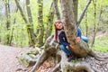 A little girl sitting astride a log in a forest