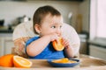 Little girl sitting in baby chair, eating an orange Royalty Free Stock Photo