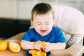 Little girl sitting in baby chair, eating an orange Royalty Free Stock Photo