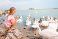 Little girl sitting on the beach with swans Royalty Free Stock Photo