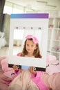 Little girl sitting on bed in bathrobe and lookin g at camera. Holding the frame Royalty Free Stock Photo