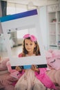 Little girl sitting on bed in bathrobe and lookin g at camera Royalty Free Stock Photo