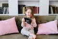 A little girl sitting on a bed holding a camera