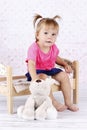 Little girl sitting on the bed holding plush toy Royalty Free Stock Photo