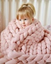 Little Girl Sitting on Bed with a Knitted Giant Plaid Royalty Free Stock Photo