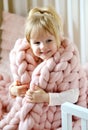 Little Girl Sitting on Bed with a Knitted Giant Plaid Royalty Free Stock Photo