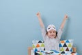 Little girl is sitting in bed in pajamas with lights on, stretching over blue Royalty Free Stock Photo