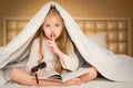 Little girl sitting on the bed and reading a book Royalty Free Stock Photo