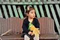 Little girl sitting on bench with bouquet of maple leaves Royalty Free Stock Photo