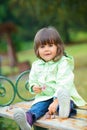 Little girl sitting on a bench in the park Royalty Free Stock Photo