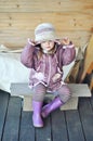 Little girl sitting on the bench on terrace of wooden house in the countryside with a Straw hat