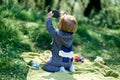 Little girl sitting on a blanket in a meadow and holds a phone. Back view Royalty Free Stock Photo