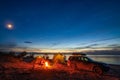 Little girl sitting at bonfire in tourist camping in the evening