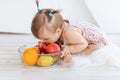 A little girl is sitting in a bright room with a plate of fruit and eating an Apple Royalty Free Stock Photo