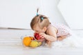 A little girl is sitting in a bright room with a plate of fruit and eating an Apple Royalty Free Stock Photo