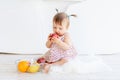 A little girl is sitting in a bright room with a plate of fruit and eating an Apple Royalty Free Stock Photo