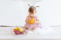 A little girl is sitting in a bright room with a plate of fruit and eating an orange Royalty Free Stock Photo