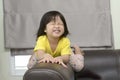 Little girl sitting on brown sofa making funny faces into the camera Royalty Free Stock Photo