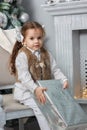 Little girl sitting in a chair with christmas box at hands. Royalty Free Stock Photo