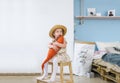 Little girl sitting on a chair and holding a toy fish in room at home. Royalty Free Stock Photo