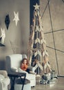 little girl sitting in a chair near the Christmas tree. Royalty Free Stock Photo