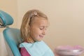 Little girl sitting in a chair near a dentist after dental treatment. Little girl sitts in the dentist`s office Royalty Free Stock Photo