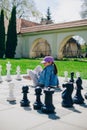 Little girl sitting on a chess board, ready to play giant chess Royalty Free Stock Photo