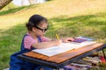 A little girl is sitting on the cloth and painted on the paper placed on a table