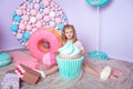 Little girl sitting in colorful room around big toyful candies, donut, lollipop Royalty Free Stock Photo