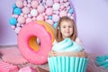 Little girl sitting in colorful room around big toyful candies, donut, lollipop Royalty Free Stock Photo