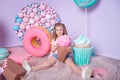 Little girl sitting in colorful room around big toyful candies, donut, lollipop Royalty Free Stock Photo