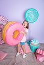 Little girl sitting in colorful room around big toyful candies, donut, lollipop Royalty Free Stock Photo