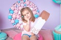 Little girl sitting in colorful room around big toyful candies, donut, lollipop Royalty Free Stock Photo