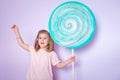 Little girl sitting in colorful room around big toyful candies, donut, lollipop Royalty Free Stock Photo