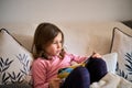 A little girl sitting on a couch and reading a book. Royalty Free Stock Photo