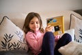 A little girl sitting on a couch and reading a book. Royalty Free Stock Photo