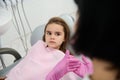 Little girl sitting in dentist chair, looking at a paediatric hygienist teaching her about oral hygiene and prevention of baby Royalty Free Stock Photo