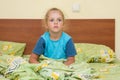 Little girl sitting on a double bed and frightened looks into distance