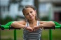 Little girl sitting on exercise equipment in the public park. Royalty Free Stock Photo