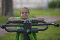 Little girl sitting on exercise equipment in the public park. Royalty Free Stock Photo