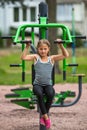 Little girl sitting on exercise equipment in the public park. Sport. Royalty Free Stock Photo