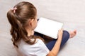 Little girl sitting on the floor and holding a white tablet Royalty Free Stock Photo