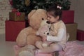 Little girl sitting on the floor with two different sizes toy bears waiting for Santa on Christmas Eve Royalty Free Stock Photo