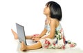 Little girl sitting on floor using a laptop, white background Royalty Free Stock Photo