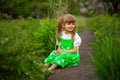 Little girl sitting on green grass in garden in summer day Royalty Free Stock Photo